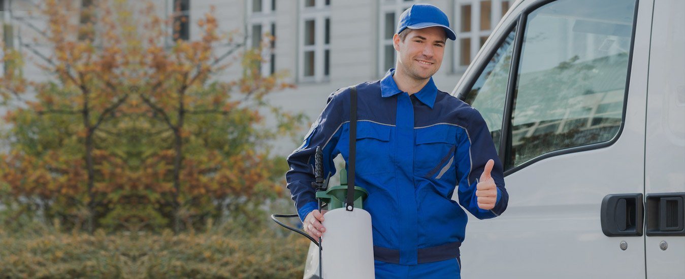Pest control technician with a sprayer standing beside a service van